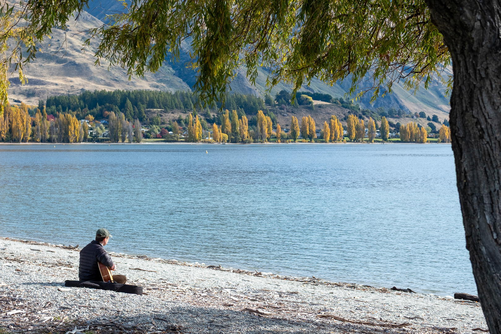 Man playing the guitar next to the lake